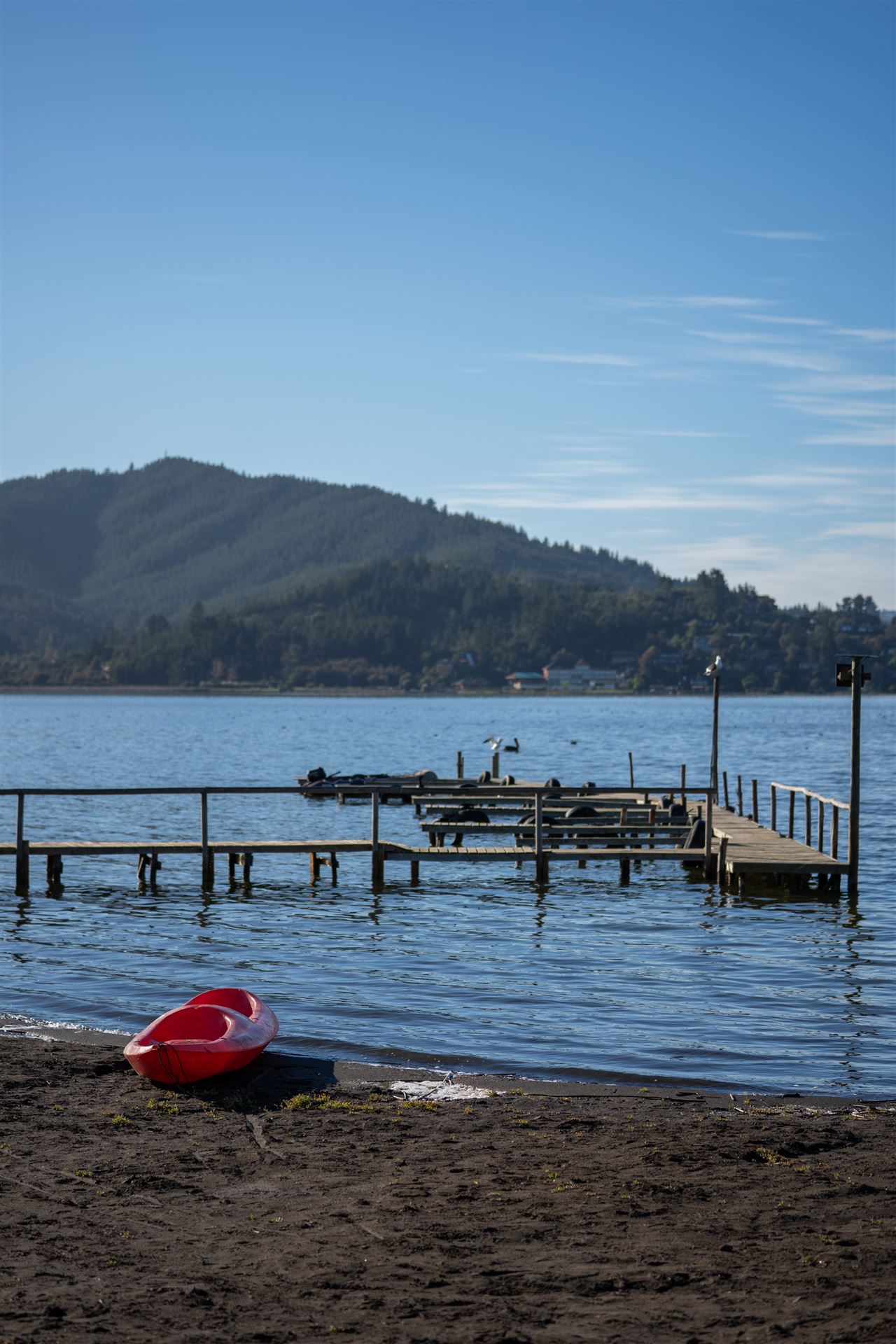 Muelle con kayak rojo y montañas